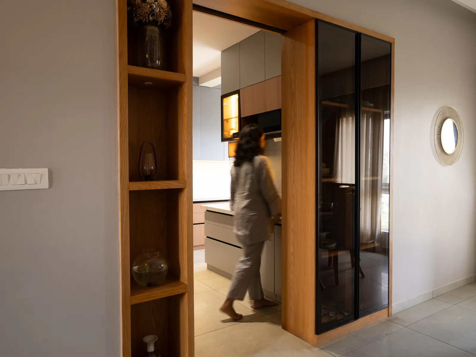 Kitchen entrance with oak shelving and glass sliding door — Amlan's Residence